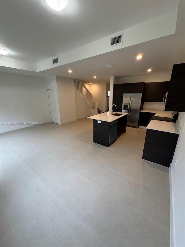 kitchen featuring stainless steel refrigerator with ice dispenser, a center island with sink, and sink