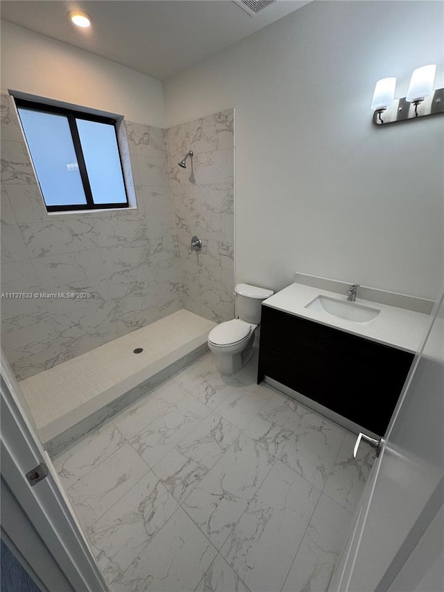 bathroom with toilet, vanity, and tiled shower