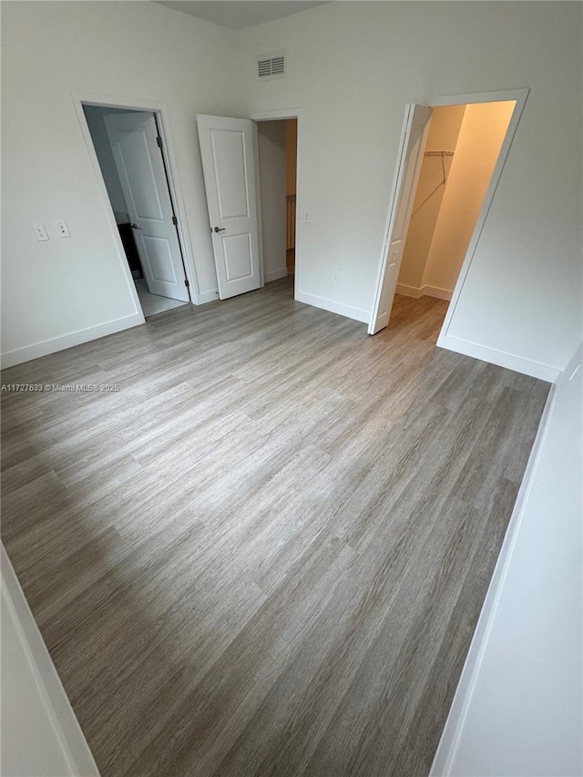 unfurnished bedroom with a walk in closet, a closet, and light hardwood / wood-style flooring