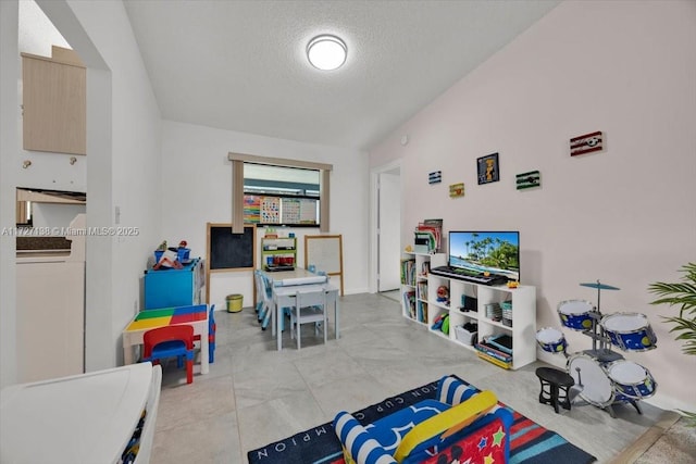 rec room with a textured ceiling, washer / dryer, and lofted ceiling