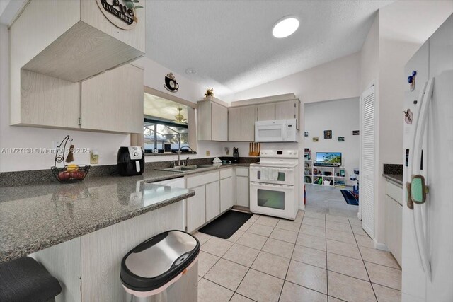 3270 Deer Lick, Kissimmee, FL 34746 - kitchen featuring white appliances, lofted ceiling, sink, light tile patterned floors, and dark stone counters