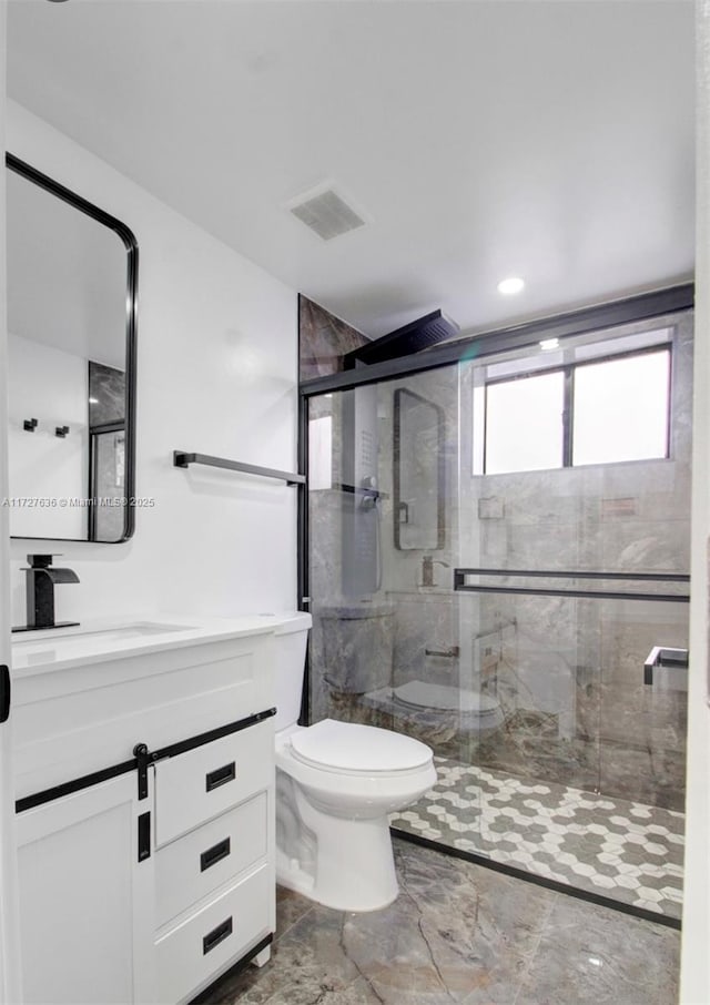 bathroom with toilet, vanity, and a shower with shower door