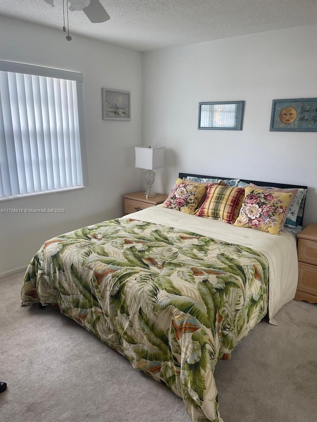 carpeted bedroom with ceiling fan and a textured ceiling