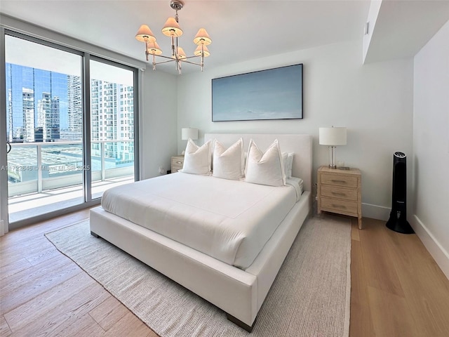 bedroom with an inviting chandelier, floor to ceiling windows, hardwood / wood-style floors, and access to outside