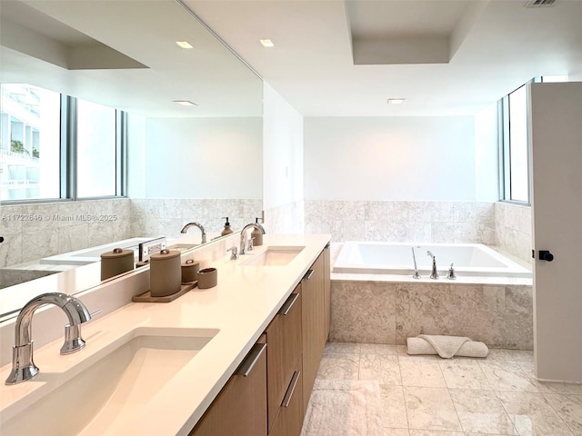 bathroom with vanity and tiled tub