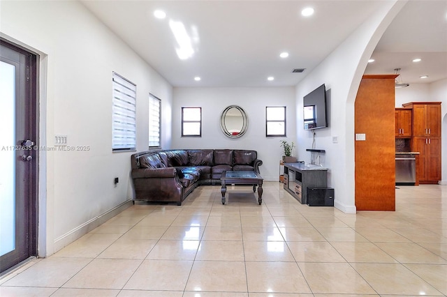 living room with light tile patterned floors, baseboards, arched walkways, and recessed lighting