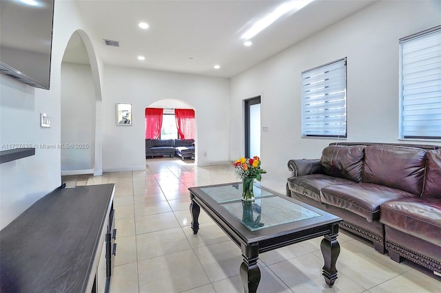 living room featuring light tile patterned floors, visible vents, arched walkways, and recessed lighting