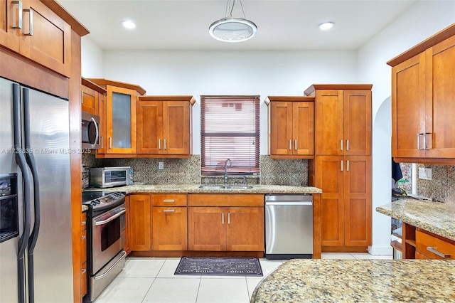 kitchen with appliances with stainless steel finishes, brown cabinets, and a sink