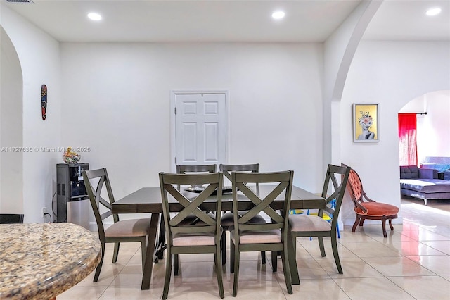 dining room with light tile patterned floors, arched walkways, and recessed lighting