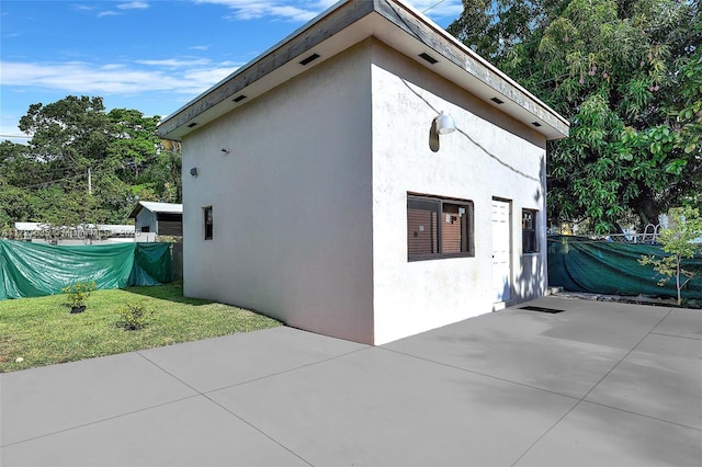 view of side of property featuring a yard, a patio, and stucco siding