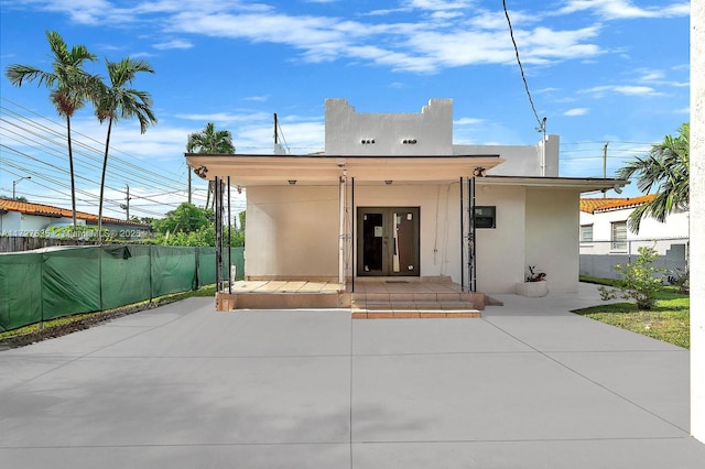 rear view of house featuring a patio, french doors, fence, and stucco siding