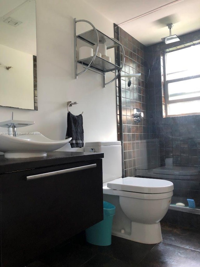 bathroom with toilet, vanity, and a tile shower