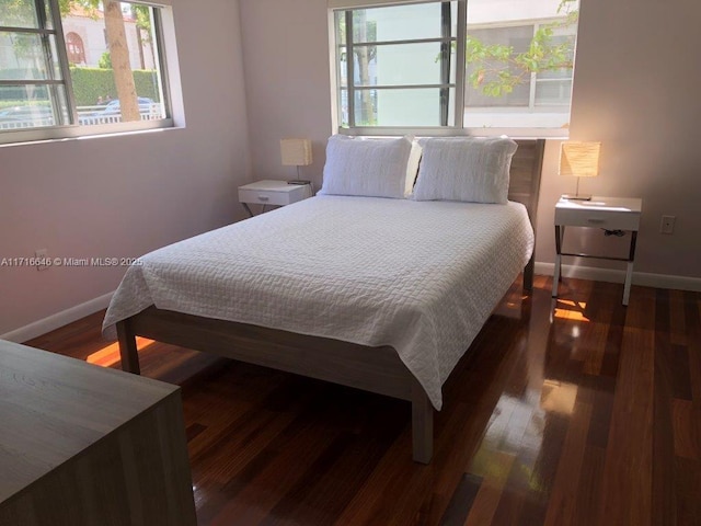 bedroom with dark hardwood / wood-style floors and multiple windows