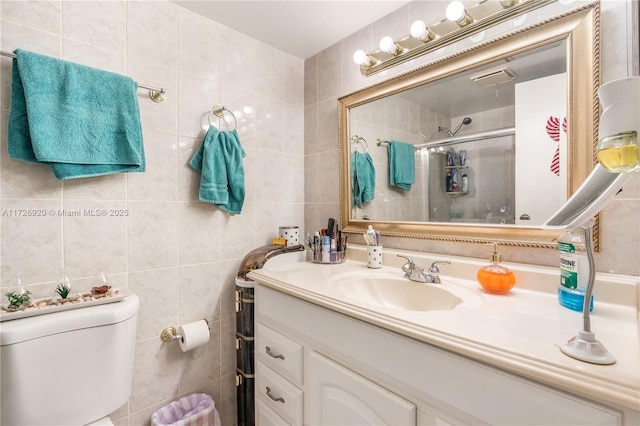 bathroom featuring a shower with shower door, tile walls, toilet, and vanity