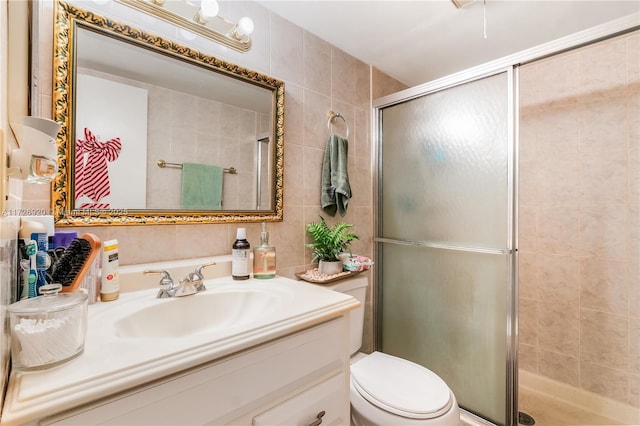 bathroom with toilet, tile walls, an enclosed shower, and vanity