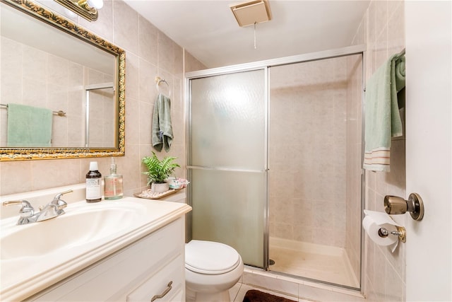 bathroom featuring toilet, tile walls, and a shower with shower door