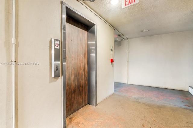 corridor with a textured ceiling and elevator