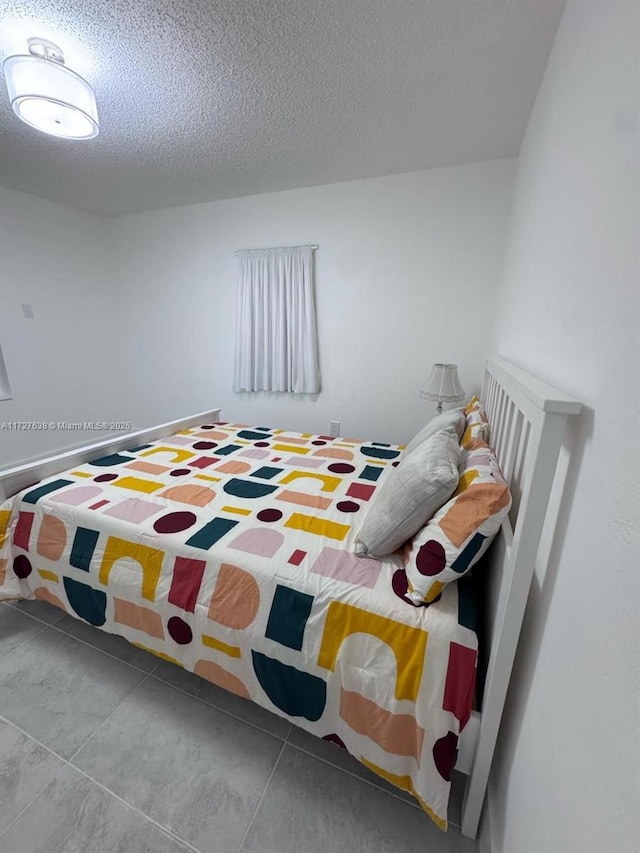 bedroom featuring light tile patterned floors and a textured ceiling