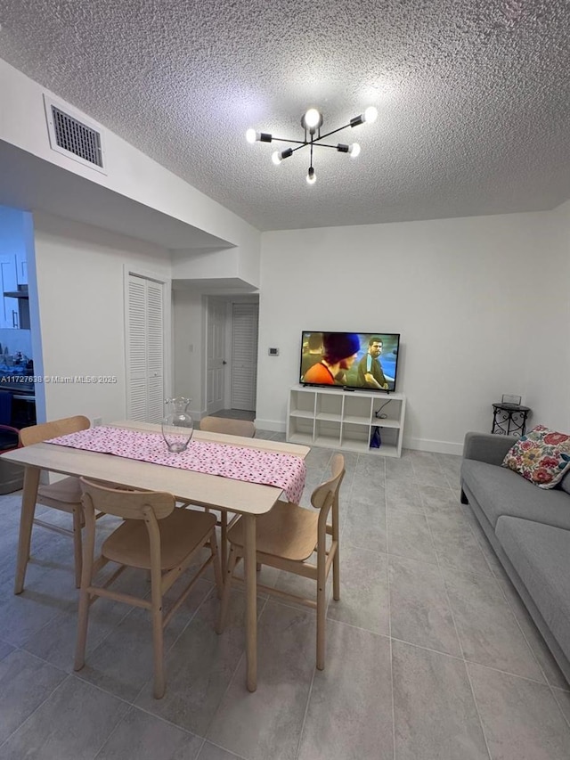 tiled dining area featuring a textured ceiling and a notable chandelier