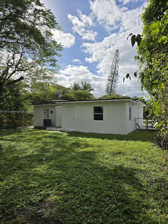 back of property with central AC unit and a yard