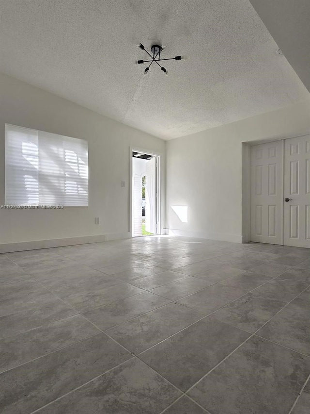 tiled empty room featuring a textured ceiling