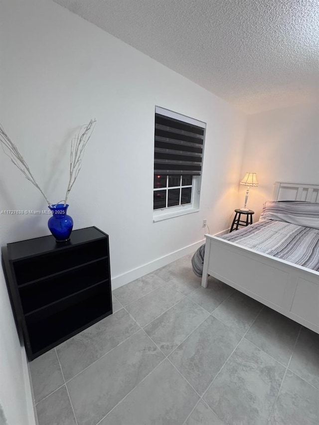 bedroom with a textured ceiling and light tile patterned flooring