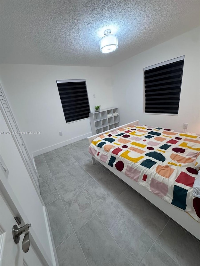 bedroom with a textured ceiling and light tile patterned floors