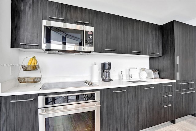 kitchen featuring appliances with stainless steel finishes, light hardwood / wood-style flooring, and sink