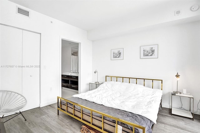 bedroom featuring ensuite bath, a closet, and hardwood / wood-style floors