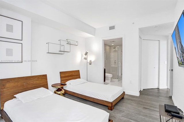 bedroom featuring ensuite bathroom and hardwood / wood-style flooring