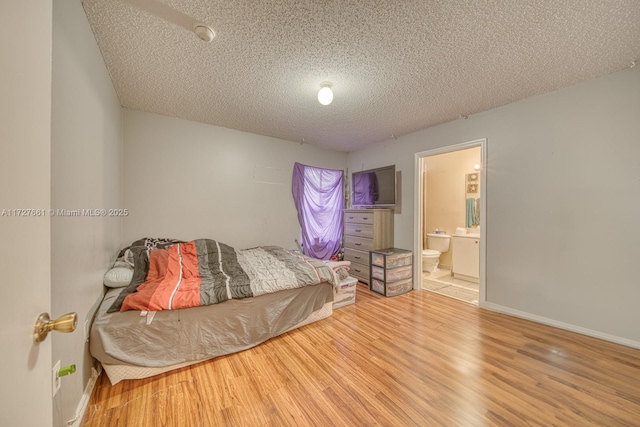 bedroom with hardwood / wood-style flooring, ensuite bath, and a textured ceiling