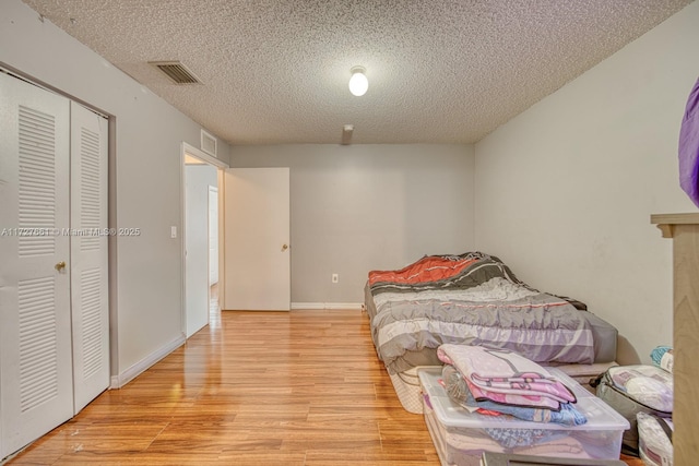 bedroom featuring a closet, light hardwood / wood-style flooring, and a textured ceiling