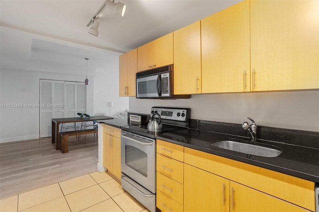 kitchen featuring light brown cabinetry, sink, dark stone counters, track lighting, and electric stove