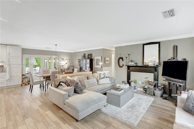 living room featuring ornamental molding, a notable chandelier, and light wood-type flooring