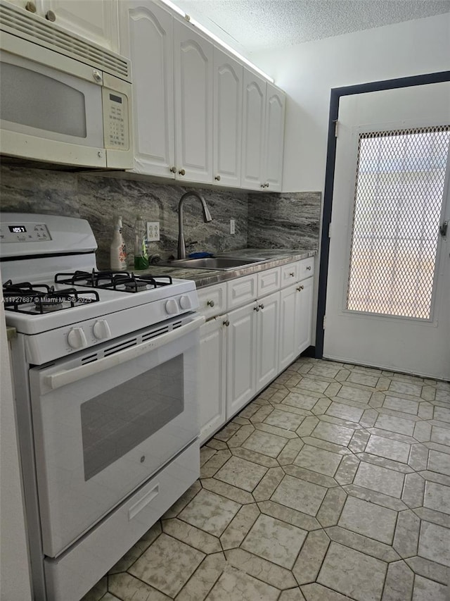 kitchen featuring decorative backsplash, sink, white appliances, a textured ceiling, and white cabinets