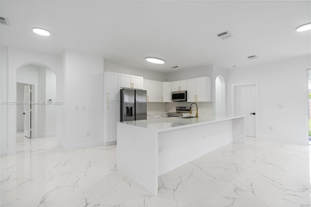 kitchen featuring kitchen peninsula, appliances with stainless steel finishes, white cabinets, and sink