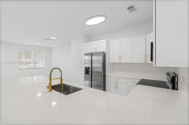 kitchen with range, white cabinets, stainless steel fridge, and sink