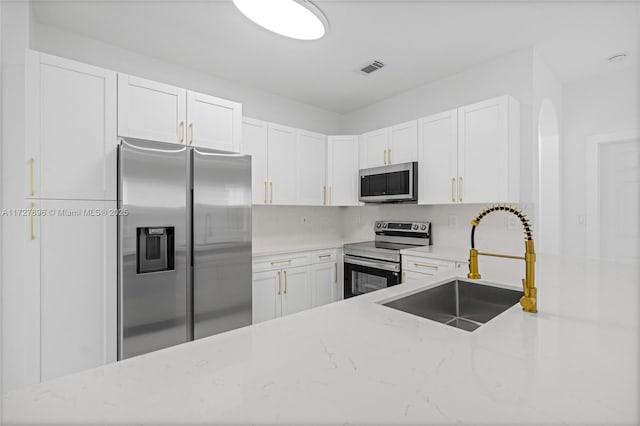 kitchen featuring light stone counters, sink, white cabinetry, and appliances with stainless steel finishes