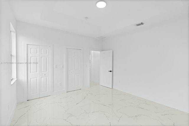 unfurnished bedroom featuring a raised ceiling