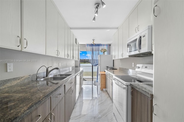 kitchen with rail lighting, electric range, dark stone counters, white cabinets, and sink