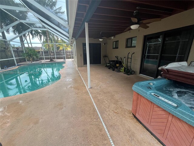 view of swimming pool featuring ceiling fan, a hot tub, glass enclosure, and a patio area