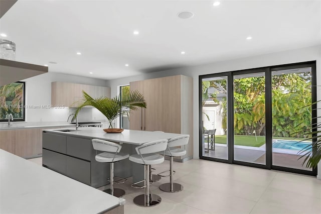 kitchen featuring sink, light brown cabinets, a breakfast bar area, and a kitchen island