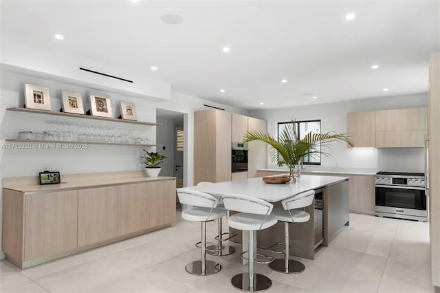 kitchen featuring a center island, a kitchen bar, light brown cabinets, stainless steel appliances, and light tile patterned floors