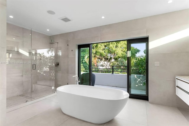 bathroom with plus walk in shower, tile walls, tile patterned floors, and vanity