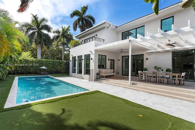 back of house with a balcony, a fenced in pool, ceiling fan, and a patio