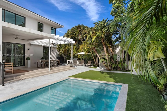 view of pool with a lawn, ceiling fan, a pergola, and a patio area