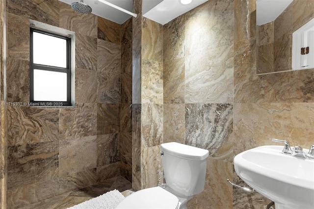 bathroom featuring toilet, tile walls, a shower, and sink