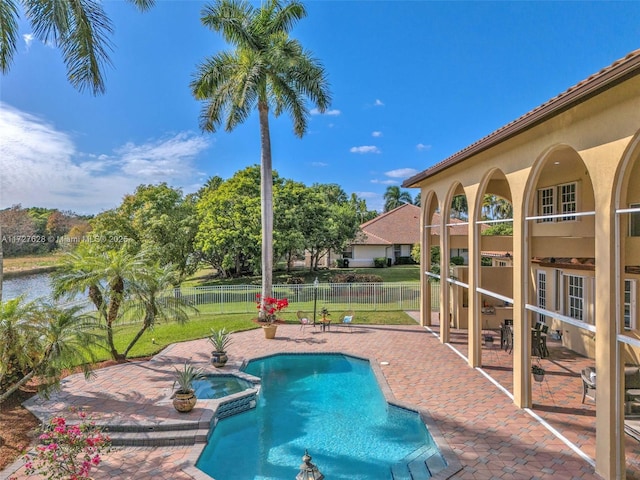 view of swimming pool featuring a water view, a patio area, and an in ground hot tub