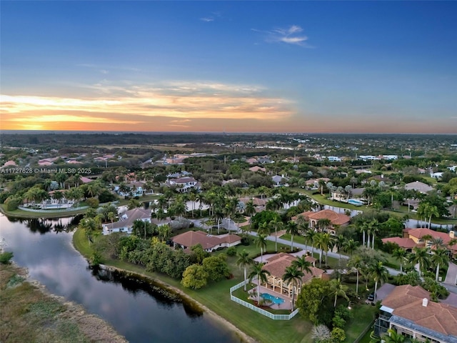 aerial view at dusk featuring a water view