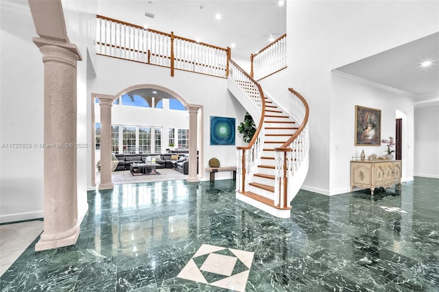 entryway with ornate columns, ornamental molding, and a towering ceiling